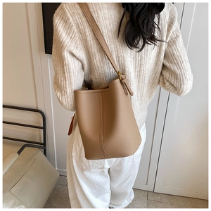 Détail d'un sac seau en cuir kaki avec surpiqûres verticales et accessoire foulard en soie