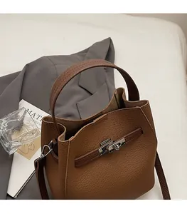 Close-up of brown litchi pattern leather bag with silver metal twist lock and handle