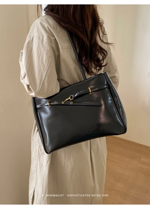 Close-up of retro black faux leather tote bag with gold hardware and elegant stitching