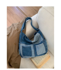 Detail of a patchwork denim hobo bag featuring dual front pockets and frayed edge design
