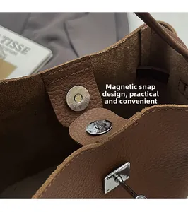Detail of magnetic buckle on brown litchi pattern leather bag with polished silver hardware