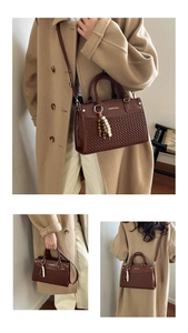 Detail view of woven leather texture and elegant beaded tassel on dark brown handbag