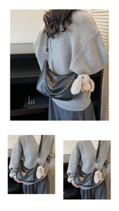 Detail of black leather crescent shoulder bag with silver chain and white rabbit pendant