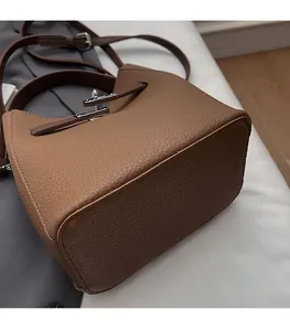 Detail of brown litchi leather bucket bag showing silver lock and precise stitching
