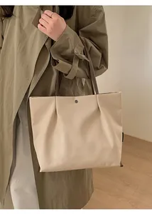 Macro detail of beige canvas tote bag with brown leather handles and metal button