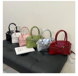 Six assorted colors of stylish shell-shaped handbags with glossy finish on a leather bench