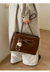 Detail of retro dark brown leather tote with gold buckle and plush bear charm