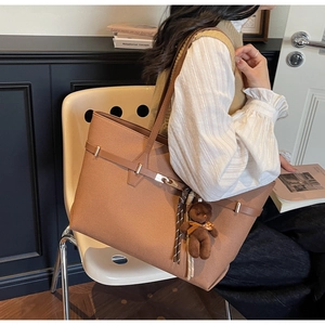 Detail of vintage caramel leather tote bag with teddy bear charm and side buckle