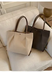 Detail view of large tote bags in beige and grey featuring premium faux leather handles