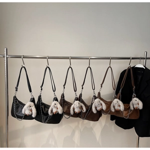 Row of leather crescent underarm bags with chain straps and plush rabbit pendants