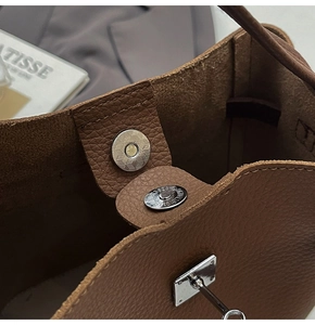 Close-up of dark brown pebble leather bag featuring a magnetic metal snap and silver buckle