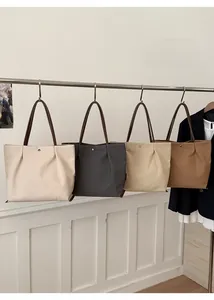 Row of canvas tote bags in cream, grey, khaki and brown hanging on a metal rack
