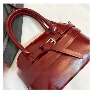 Macro detail of wine red glossy handbag featuring leather strap buckle and metal hardware