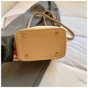 Détail du fond d'un sac seau beige en cuir grainé avec quatre clous dorés protecteurs