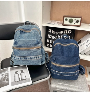 Detail view of vintage denim backpack featuring double front zippers and side pockets