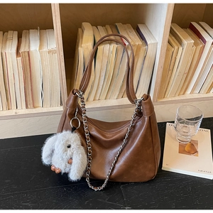 Detail of brown hobo tote bag with chain strap and cute plush rabbit charm on side