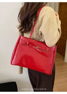 Detail of a large red glossy tote bag showing high-shine leather texture and metal buckle