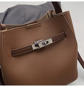 Detailed macro view of dark brown pebbled leather texture and silver buckle on bucket bag