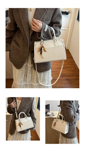 Detail of white woven PU handbag with wood bead charm and adjustable shoulder strap