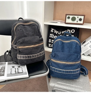 Detail view of retro washed denim backpacks in black and blue colors with metal zippers