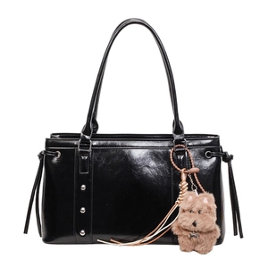 Glossy black leather tote bag with silver rivets and a cute brown plush dog charm accessory