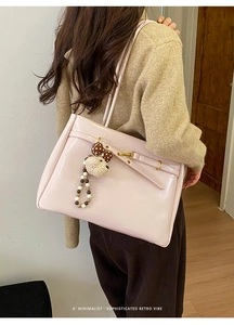 Close-up of pink glossy tote bag with metal buckle and cute dog charm on shoulder