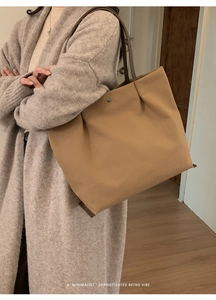 Detail of khaki canvas tote bag featuring brown leather straps and metal snap button closure