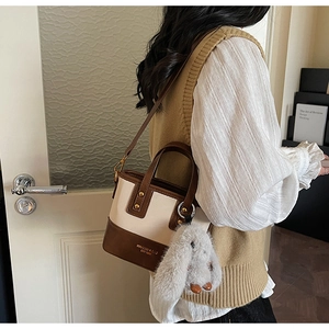 Dettaglio della mini borsa bicolore con manico marrone e ciondolo a forma di coniglio