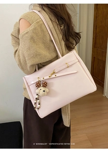 Close-up of pink leather tote bag with gold hardware and a cute teddy bear charm