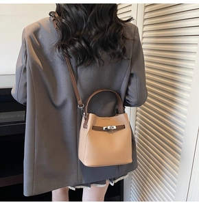 Detailed view of pebbled leather bucket bag with silver lock and brown handles