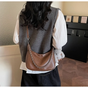Close-up of vintage brown leather crescent bag with silver chain and cute bear charm