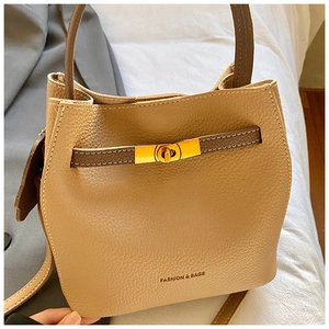 Détail du sac seau en cuir grainé avec fermoir rotatif doré et texture raffinée