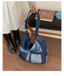 Detail of denim patchwork tote bag featuring frayed edges and adjustable shoulder strap