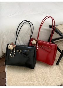 Detail of high-gloss black and red tote bags with bear charms and gold hardware