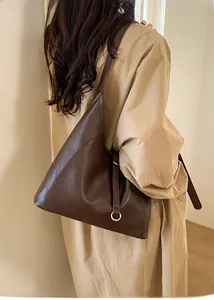 Detail of dark brown tote bag showing silver ring hardware and premium leather texture