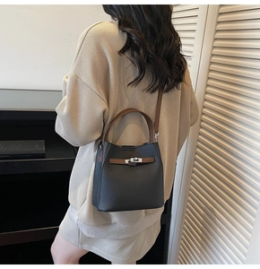 Detail of vintage black pebbled leather bucket bag with brown strap on a model