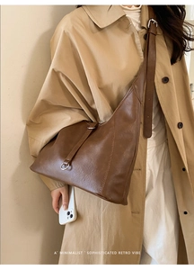 Detail of dark brown retro crescent tote bag with silver ring on beige trench coat