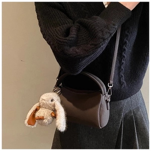 Detail der dunkelbraunen Boston-Tasche mit flauschigem Hasenanhänger am Modell getragen