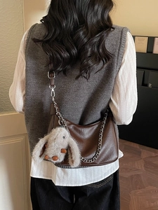 Deep brown leather hobo bag with silver chain detail and plush rabbit pendant on shoulder