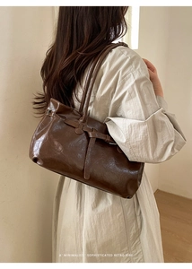 Minimalist dark brown tote bag in vintage faux leather worn by a model on her shoulder