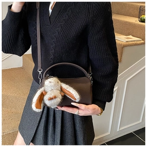 Detail der dunkelbraunen Boston-Tasche aus Leder mit niedlichem Plüschhasen-Anhänger