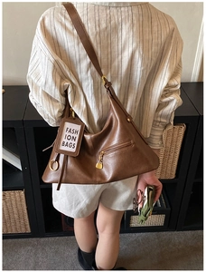 Detail of a brown vintage leather shoulder bag with gold heart zipper and fashion tag