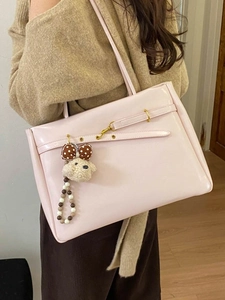 Pink patent leather tote bag with gold buckle and plush puppy charm on model