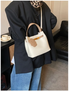 Détail du sac seau en cuir grainé blanc avec breloque d'ours et fermoir métallique