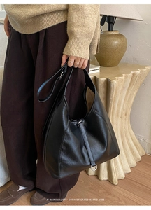 Détail du sac hobo rétro noir avec texture en cuir mat et boucle métallique décorative