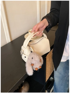Detail der cremefarbenen Boston-Tasche mit Lychee-Narbenleder und Plüschhasen-Anhänger