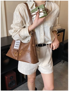 Detailed view of the brown leather tote bag with gold hardware and fashion patch