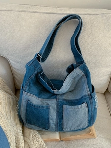 Large denim patchwork tote bag with frayed edges on a cozy beige sofa background