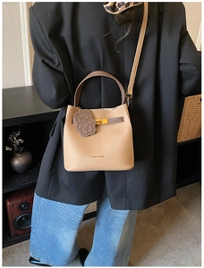 Détail du sac seau en cuir camel avec fermoir doré et accessoire de charme ours brun