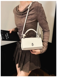 Detail of off-white lychee pattern handbag featuring silver twist lock and knotted handle